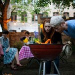 Young friends preparing barbecue grill at garden party